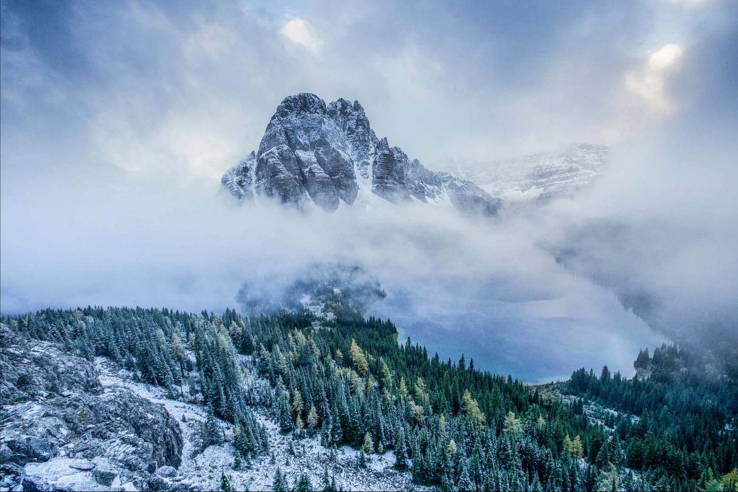 A tall mountain after a snowstorm, with clouds rolling through the valley below